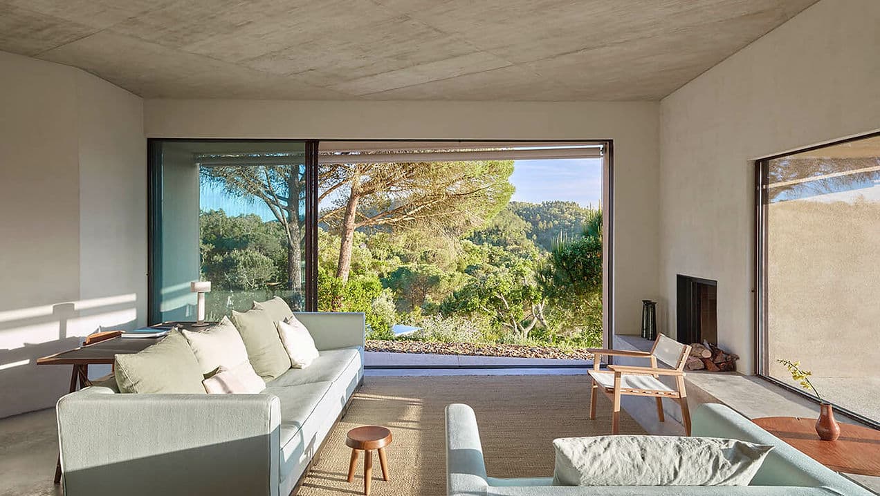 Living room with large windows overlooking forested landscape at Cá na Serra Melides Portugal holiday rental