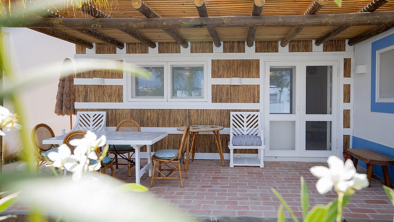 Outdoor dining patio with wooden pergola and rattan seating at Casa Mounette Portugal