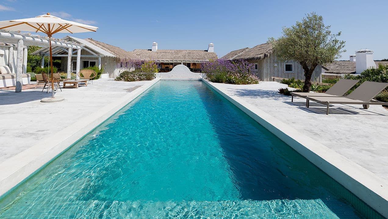 Outdoor swimming pool with sun loungers and umbrellas at Rafter Comporta Celeste in Comporta, Portugal
