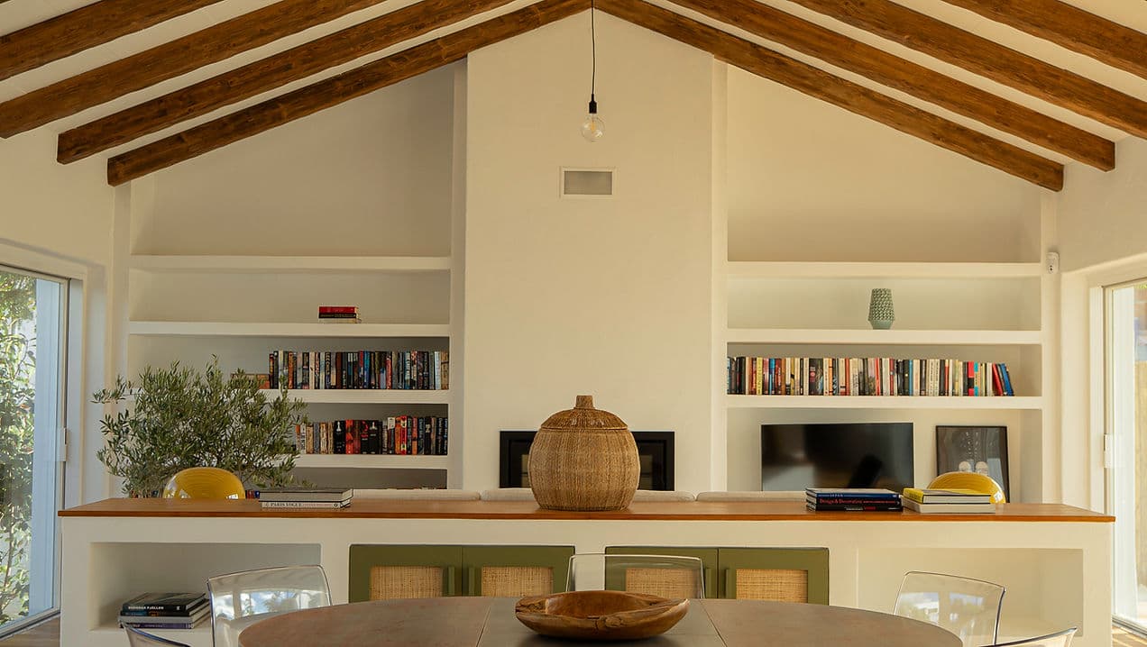 Living room with vaulted wood beam ceiling and built-in bookshelf at Rafter Melides Oliveiras in Melides, Portugal