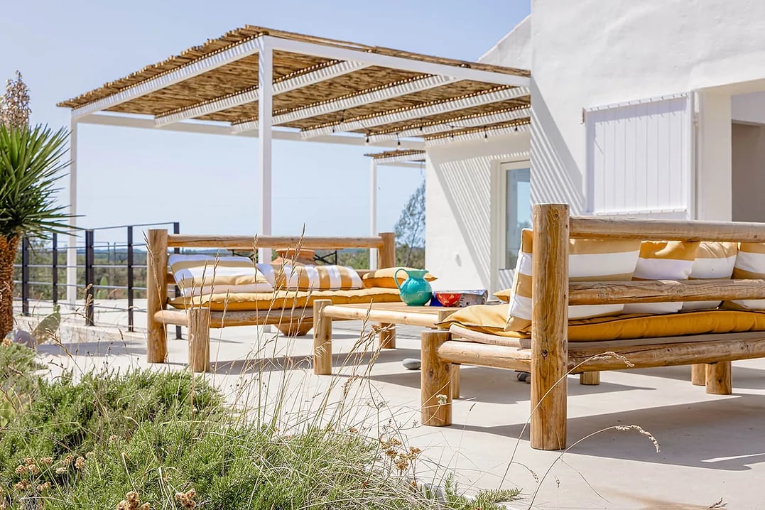 Outdoor lounge area with wooden furniture and shaded pergola at Casa Acima in Santiago do Cacém, Portugal