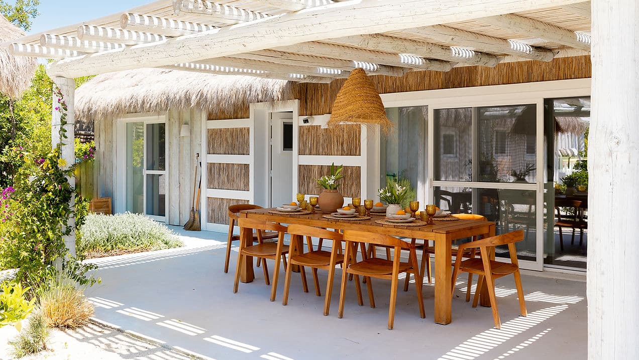 Outdoor dining area with wooden table and chairs under shaded pergola at Rafter Comporta Celeste in Comporta, Portugal