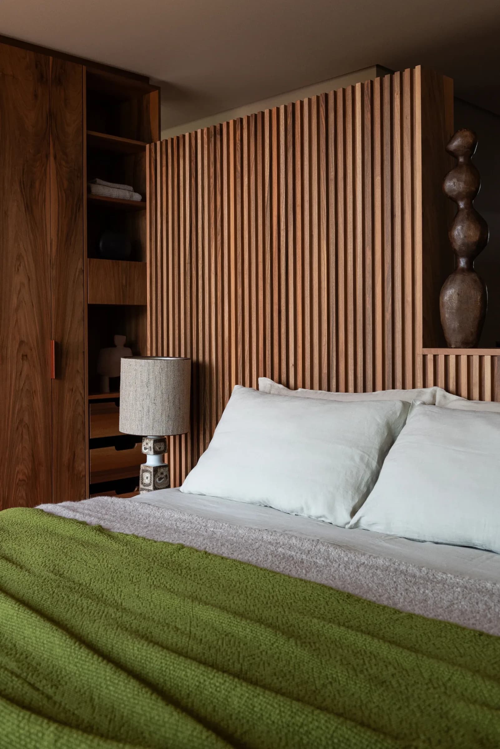 Double bed with white pillows and green blanket against wooden paneled wall at Rafter Merano Algund