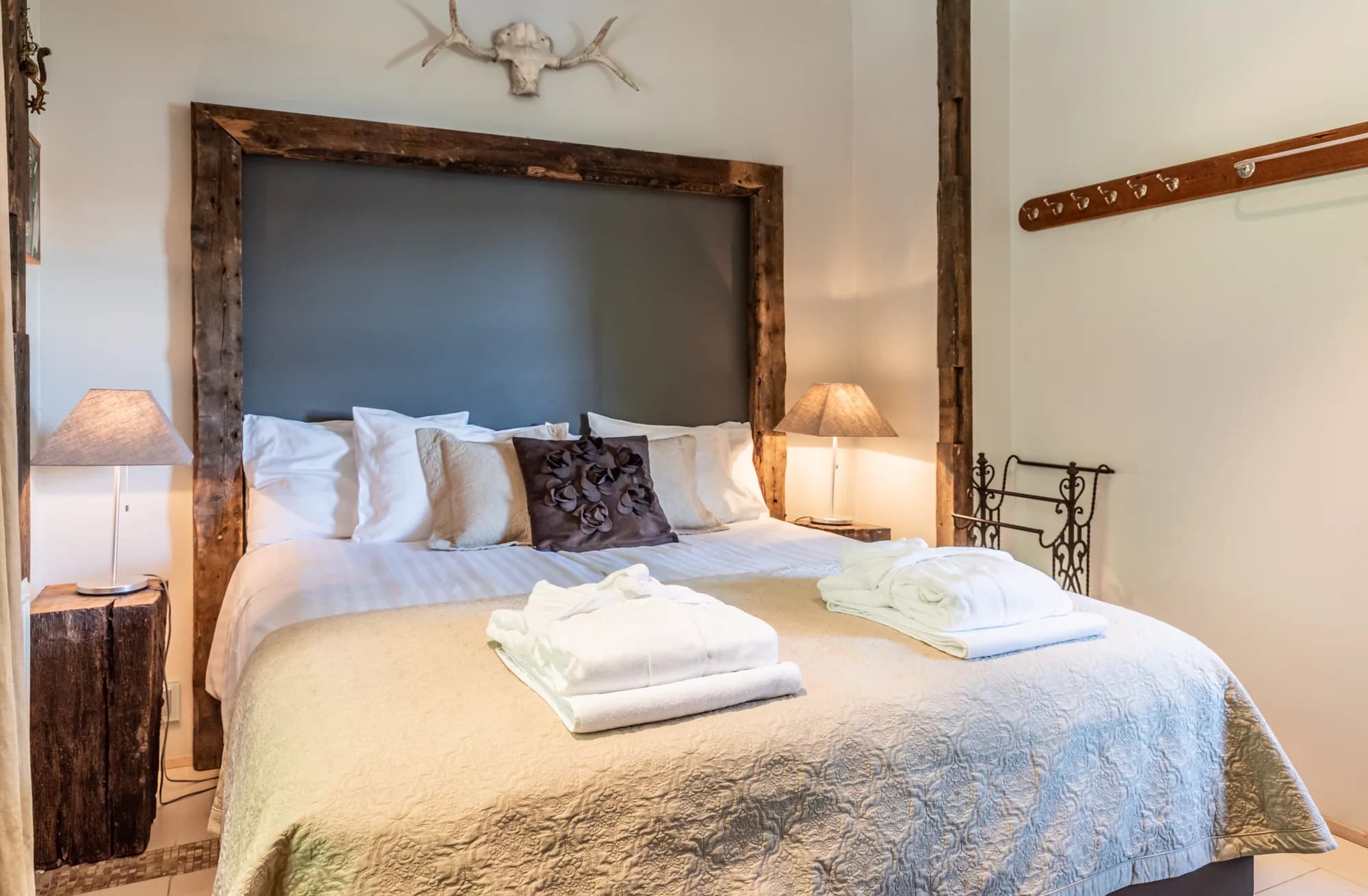 Double bed with rustic wooden headboard and bathrobes in Rafter Aslundur bedroom, Iceland