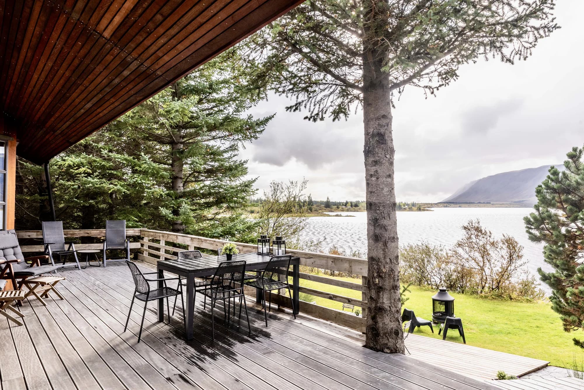 Outdoor deck with dining set and lake view at Rafter Aslundur in Iceland for nature retreats