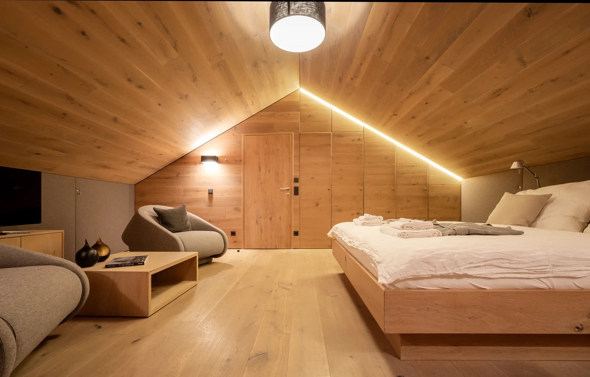 Loft bedroom with wooden walls, modern seating, and ambient lighting at Rafter Bramberg, Austria