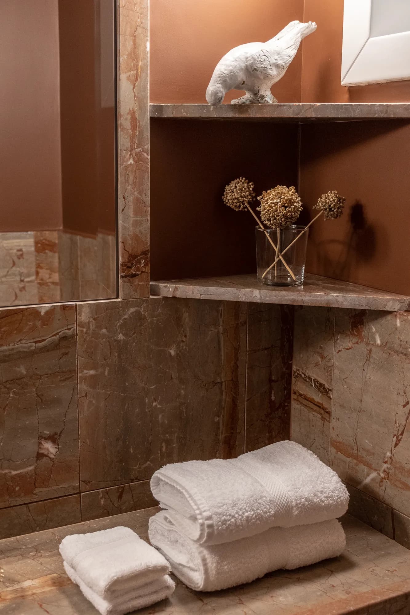 Stacked white towels and decorative dried flowers on marble shelves in Rafter Koufonisia Doto bathroom
