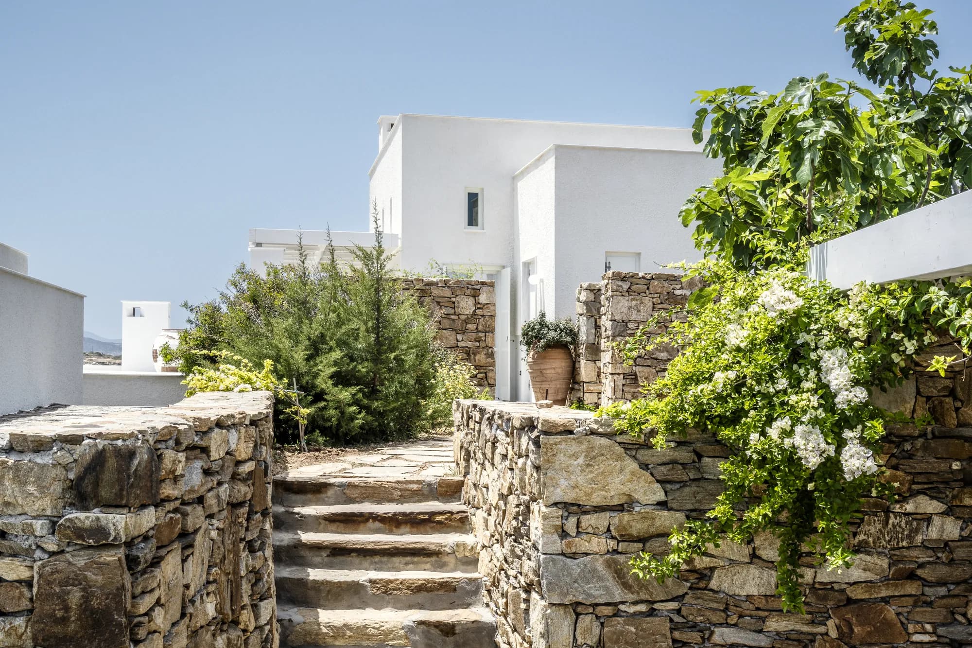 Stone steps and rustic walls leading to a white villa exterior at Rafter Koufonisia Doto in Koufonisia, Greece