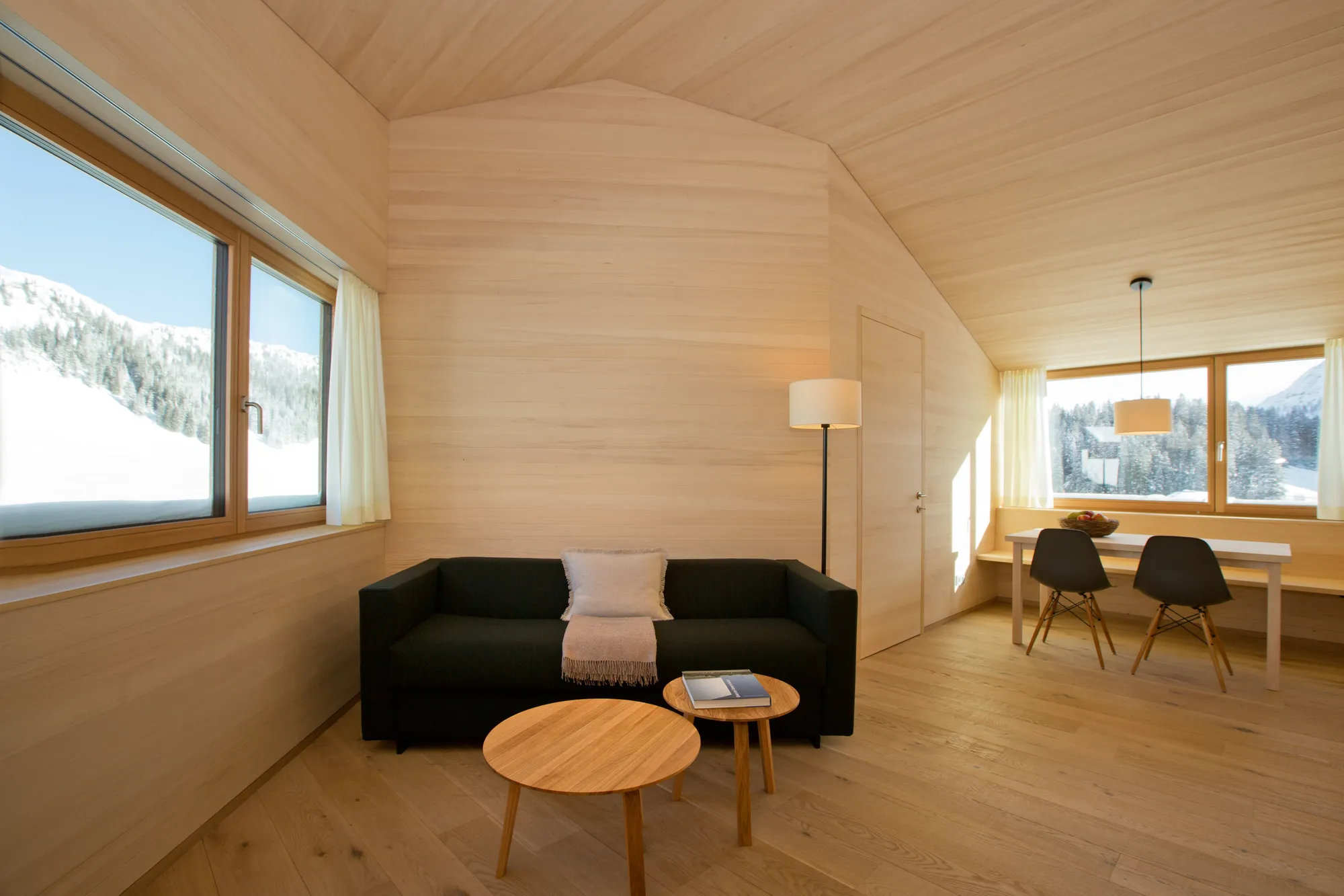 Living room with black sofa and snowy mountain views at Rafter Warth in Warth, Austria