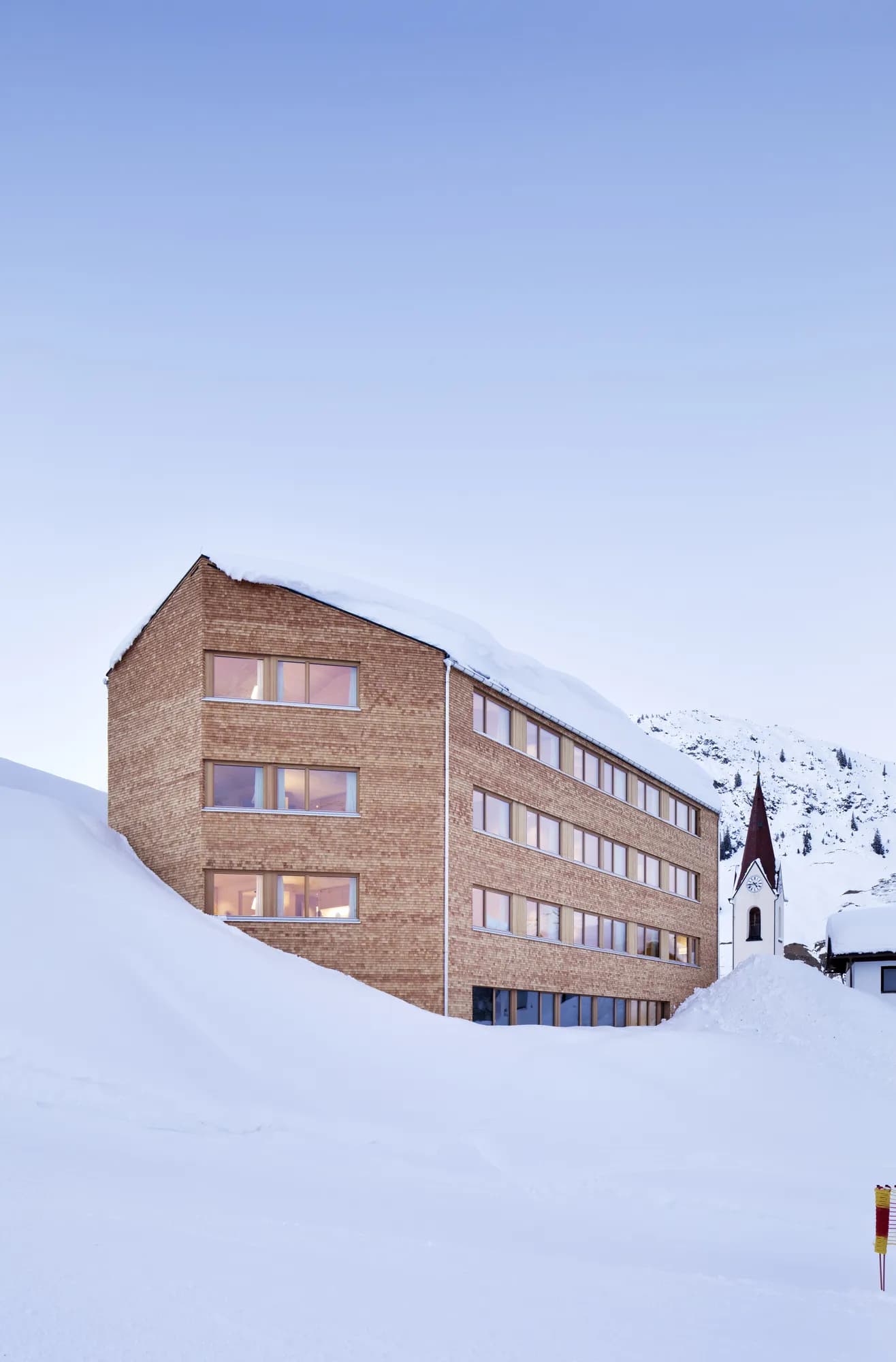 Rafter Warth exterior with large windows set against snow-covered mountains in Warth, Austria winter scenery