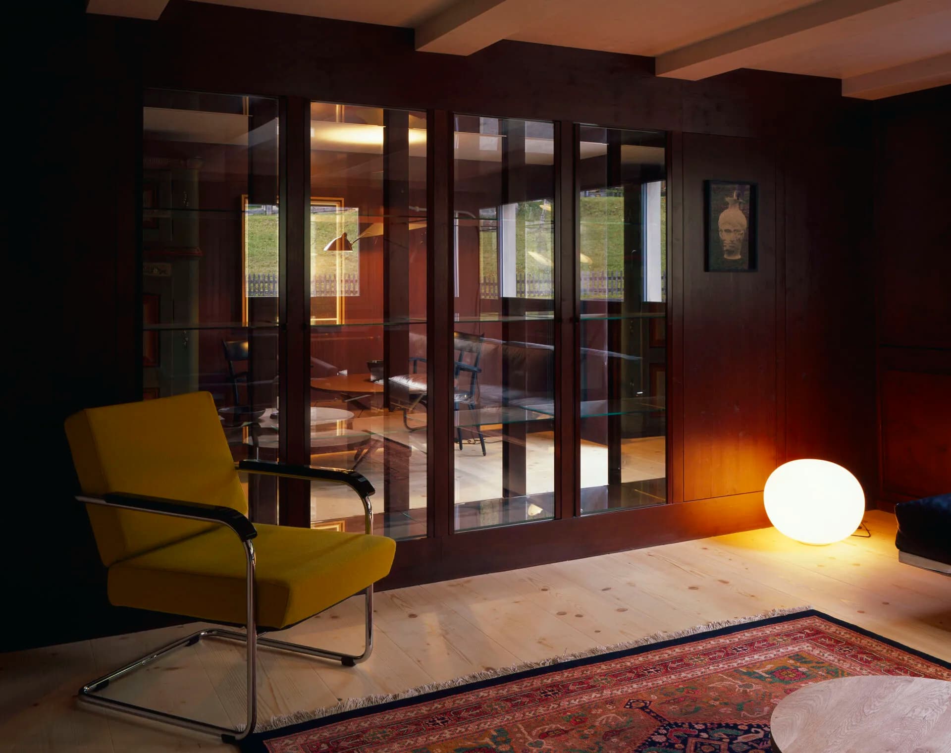 Living room with yellow armchair and glass-front cabinet at Rafter Tschiertschen in Switzerland